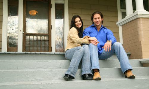 happy couple sitting on steps of new home