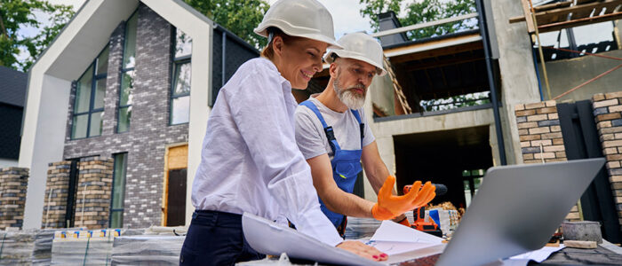 woman and man looking at house plans at construction site