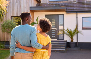 man and woman standing in front of a house