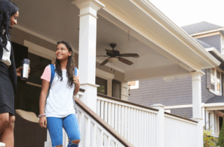 Businesswoman Mother Walking Daughter To School On Way To Work