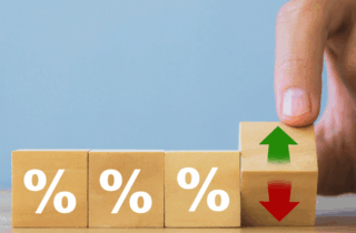 Hand holding wooden block with arrow and percentage symbol