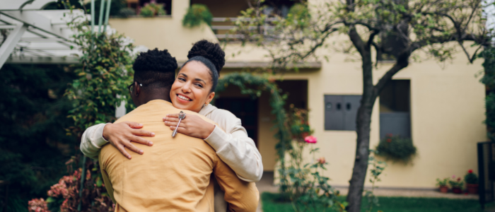 Woman Hugs Partner in Front of House